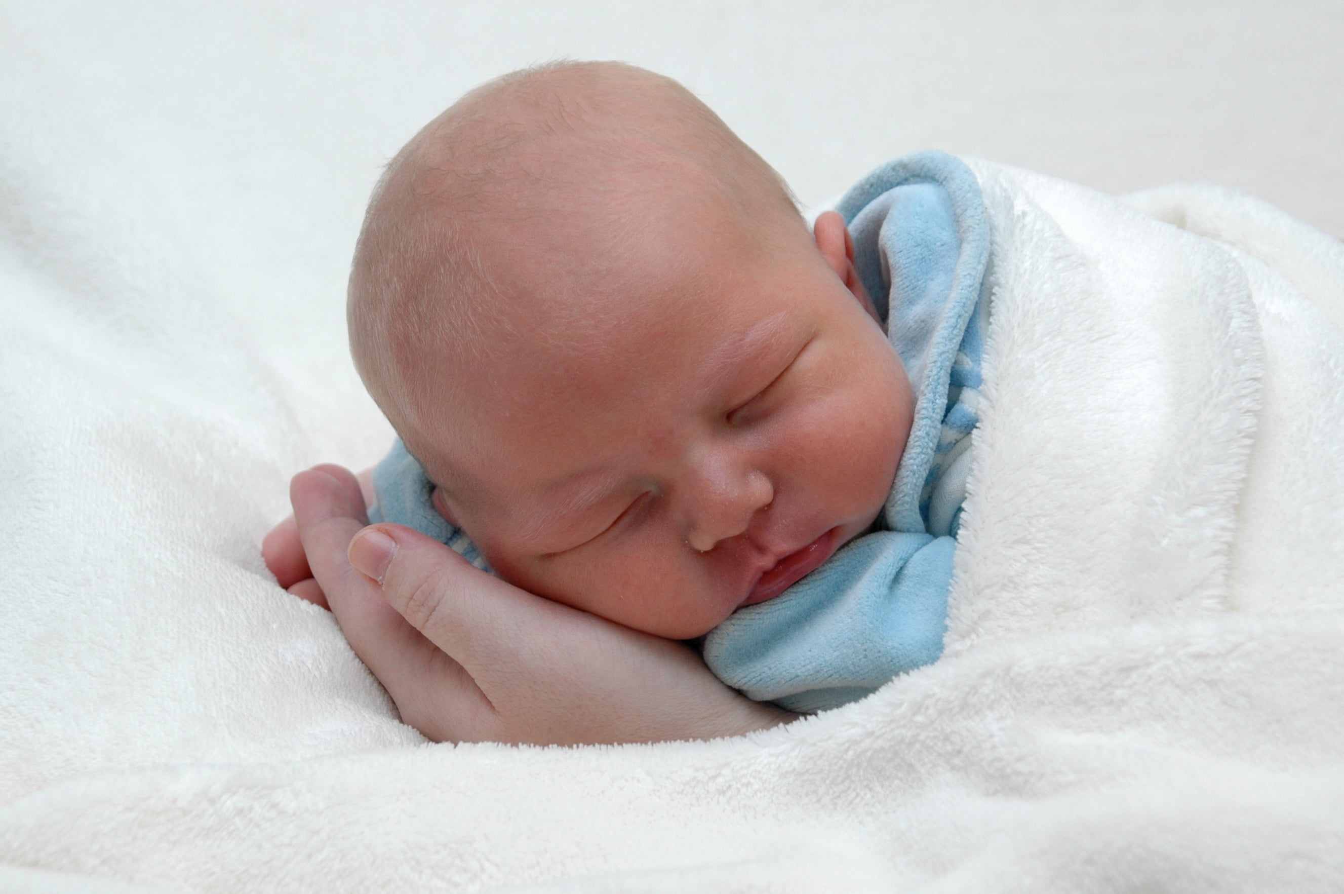 sleeping baby on white textile in close-up photography, child