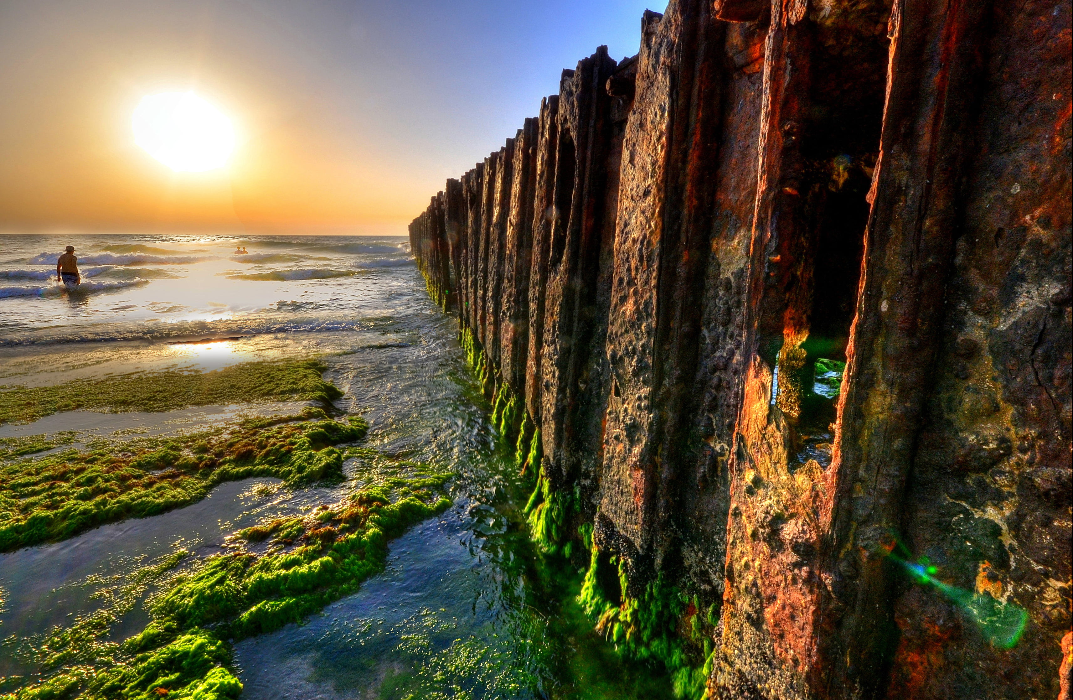 rusty metal dock covered with moss during sunset, beach, sea  waves