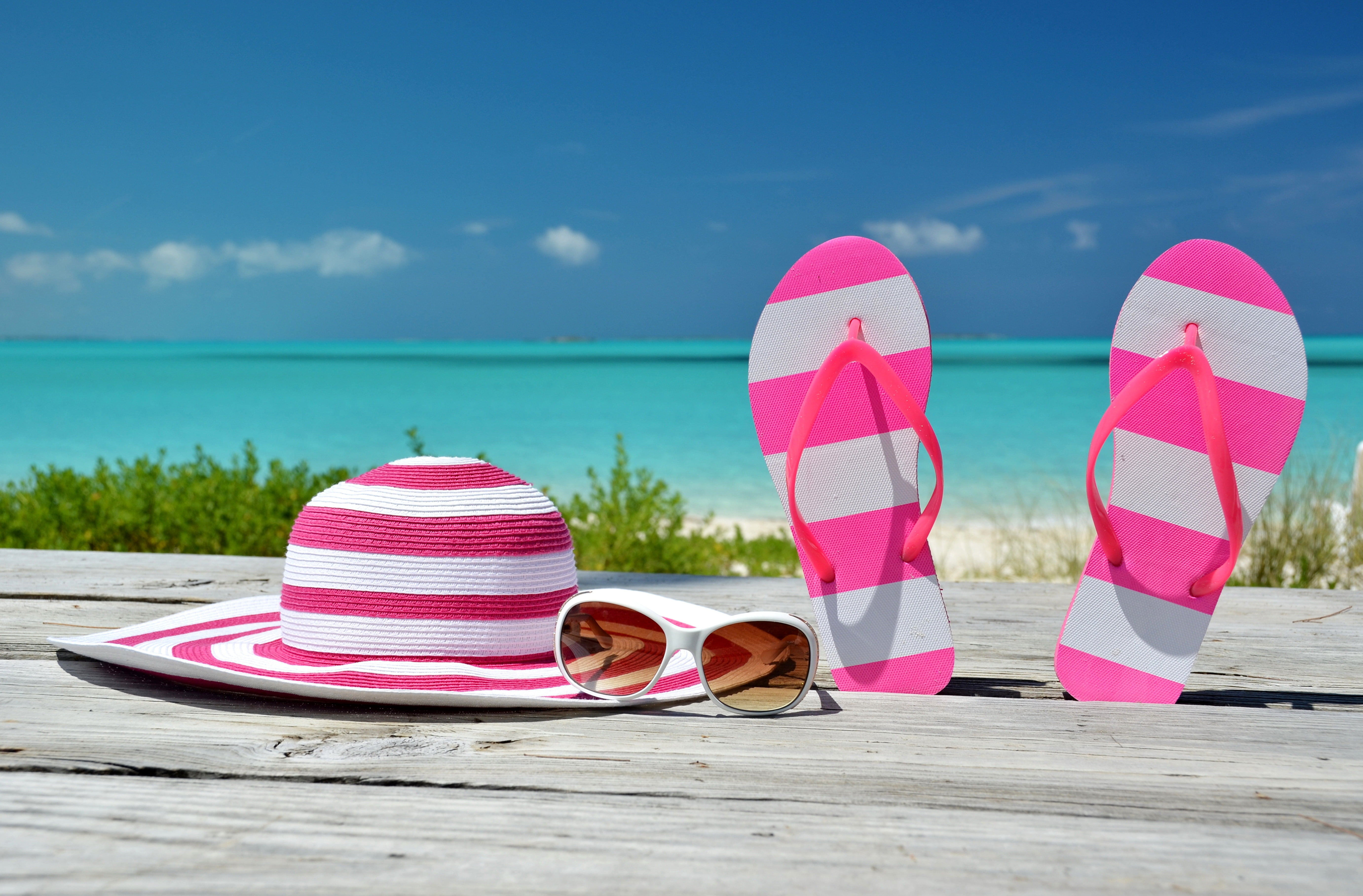pair of pink-and-white striped flip-flops and sun hat, sea, beach