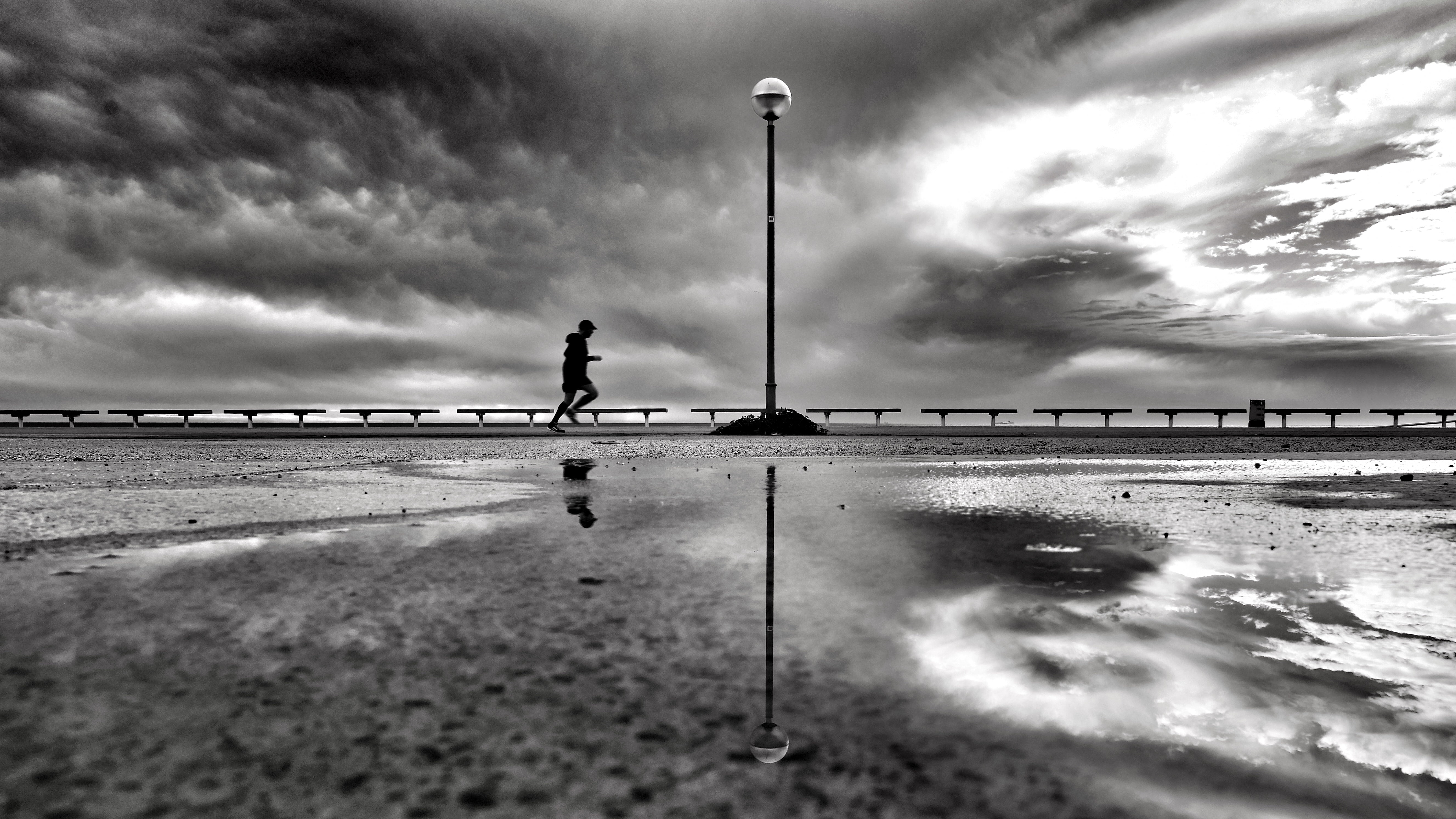 gray scale photo of person jogging near to body of water, morning