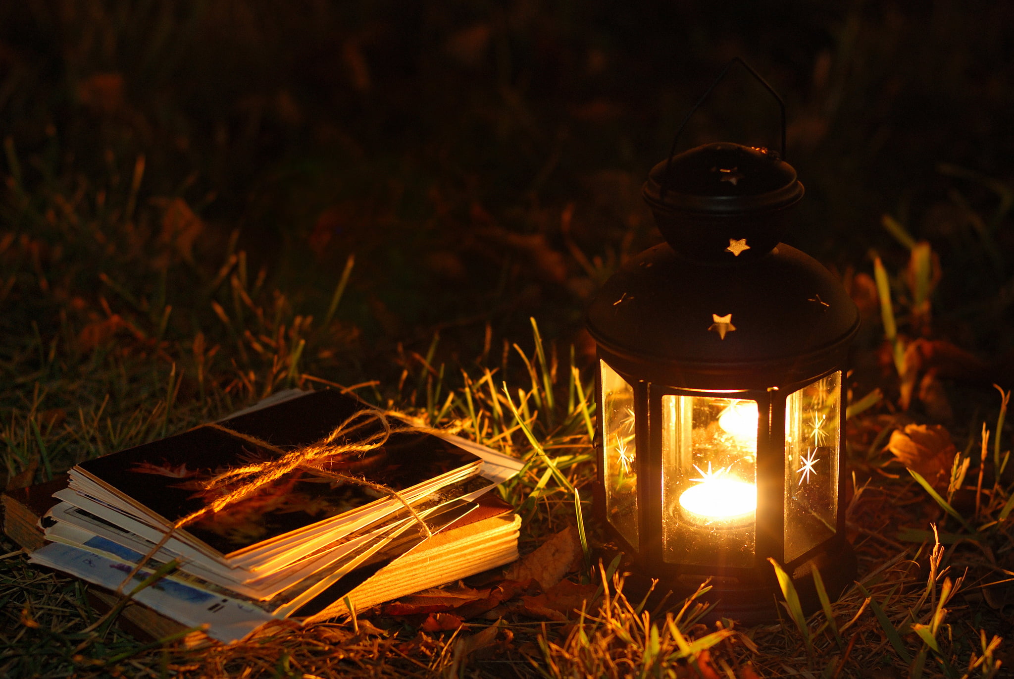 black metal candle lantern, grass, leaves, flashlight, letters