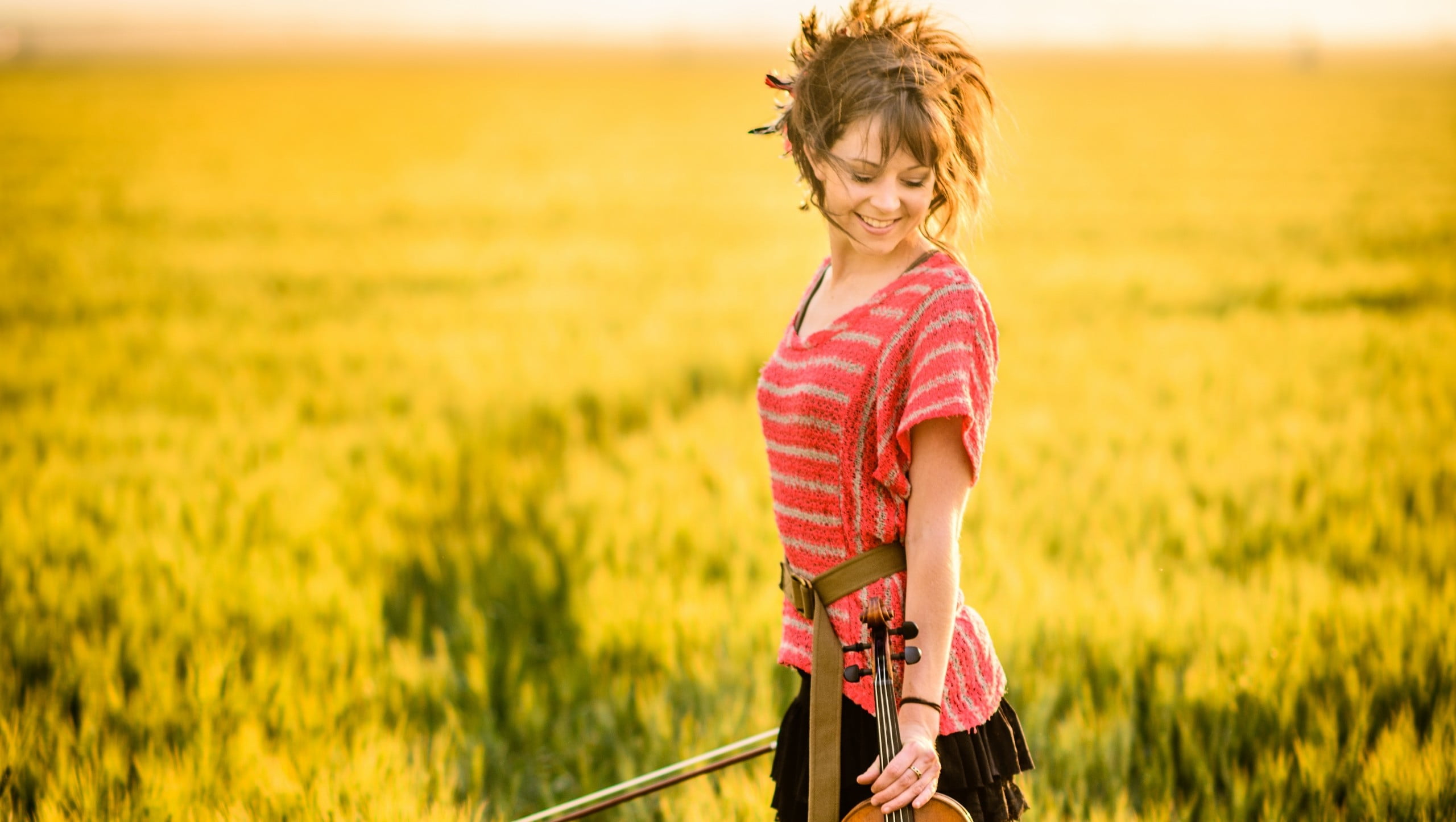 woman wearing pink and white striped shirt carries violin, Lindsey Stirling