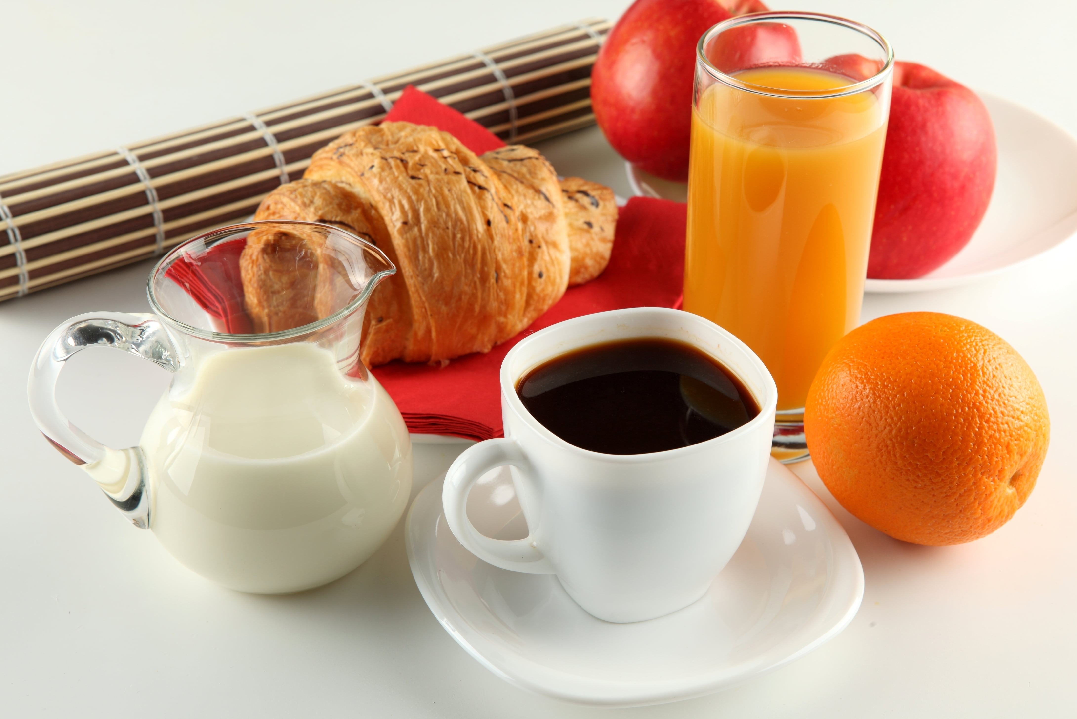 white ceramic mug, white ceramic saucer, clear pitcher, orange fruit, and orange juice