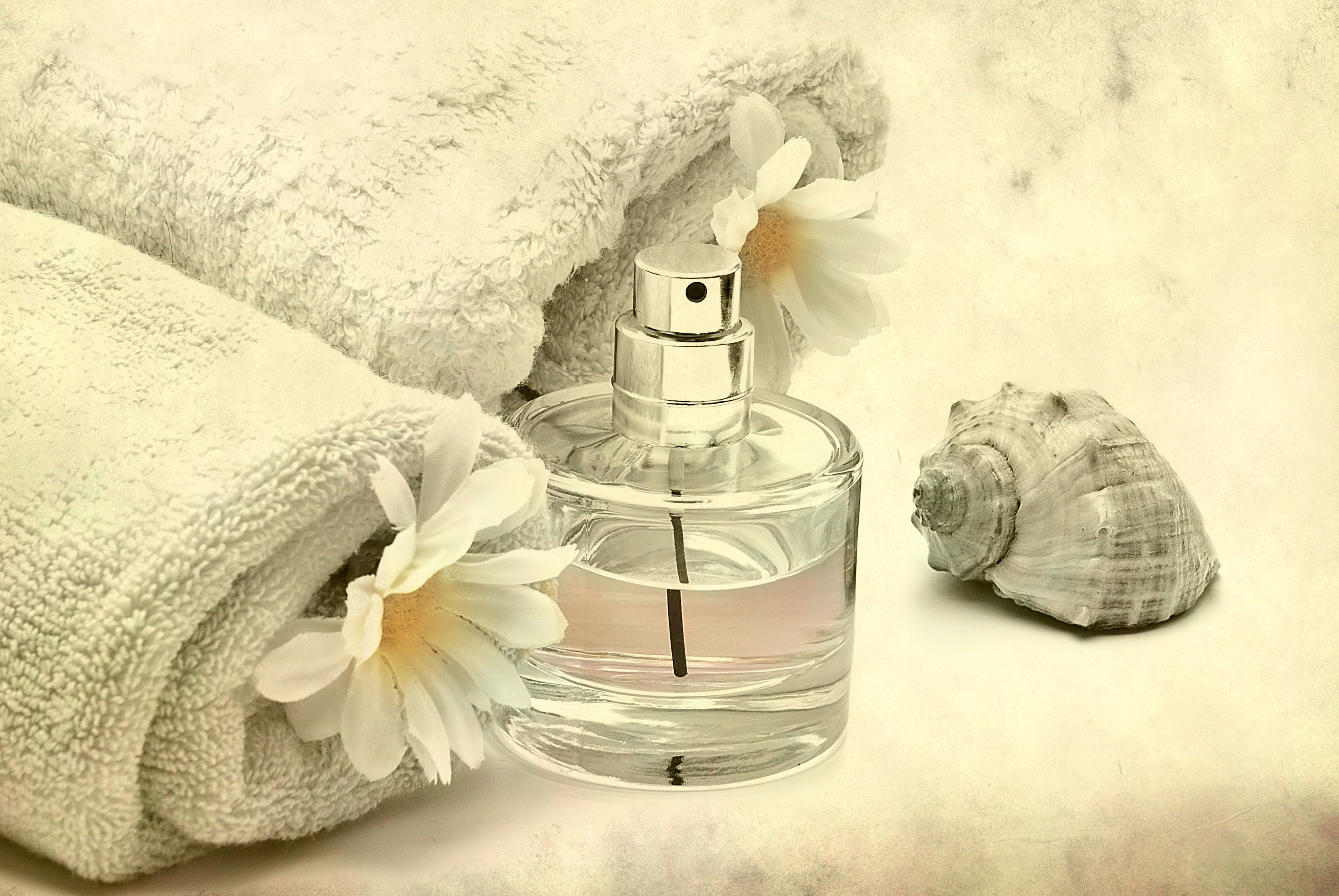 clear glass perfume bottle, water, flowers, towel, relaxation