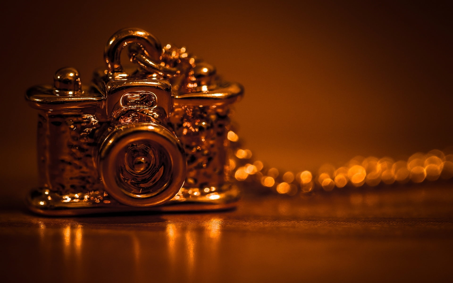 gold-colored DSLR camera pendant necklace in selective focus photography
