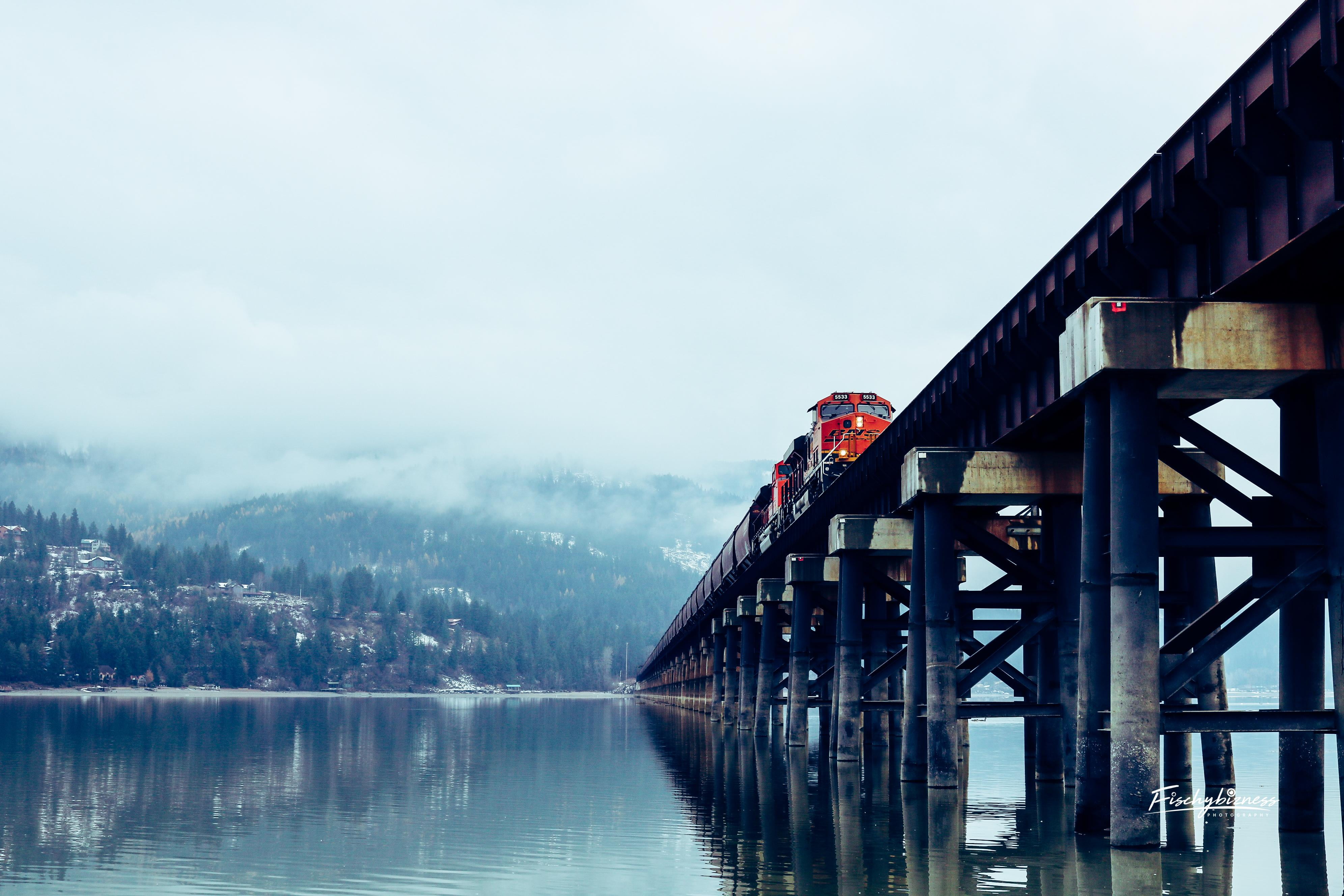 red and black train, bridge, water, trees, mountains, clouds