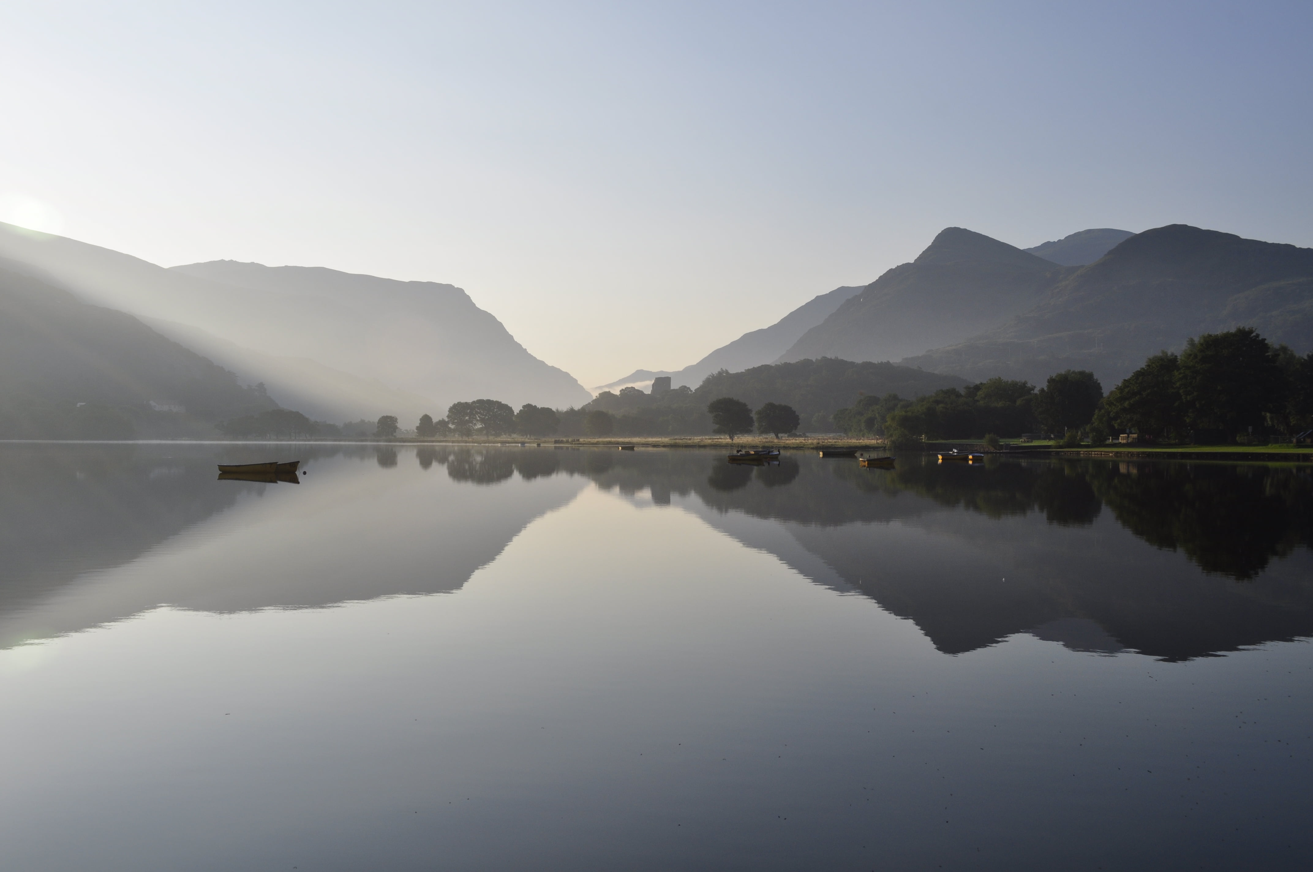 calm body of lake surrounded with mountains under blue sky at daytime, llanberis, llanberis