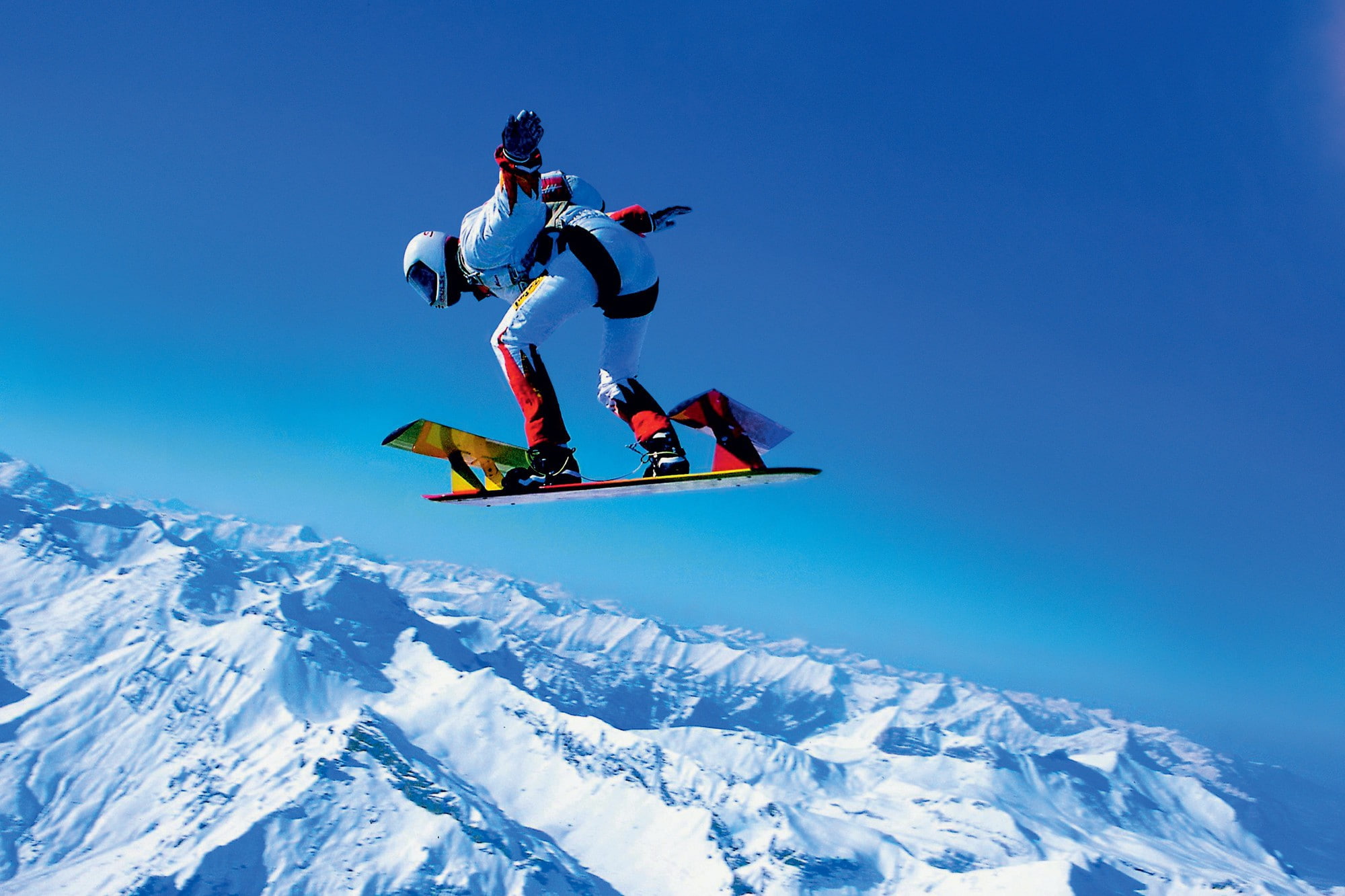 Parachutists, man in white and black suit and white helmet riding on snowboard