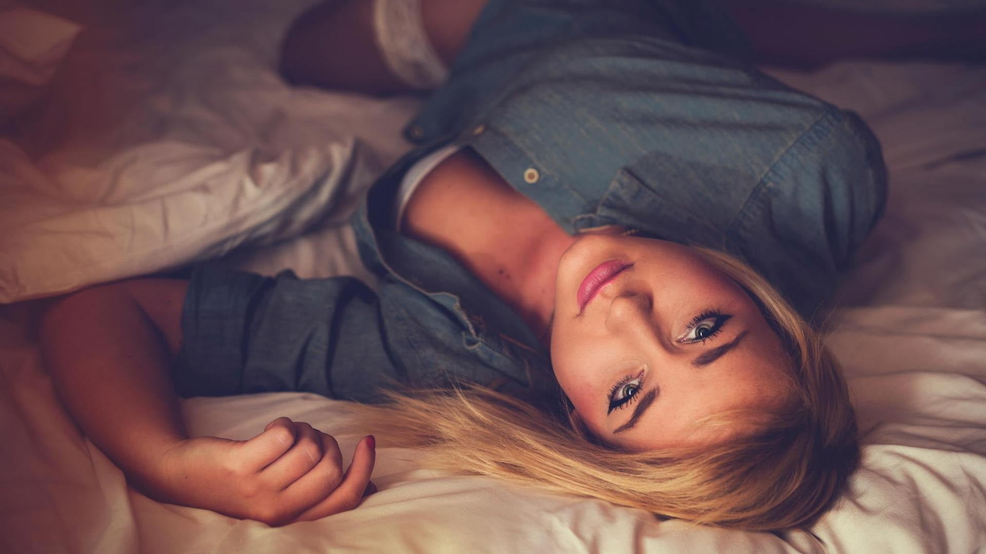 woman wearing blue denim jacket lying on brown bedspread, women