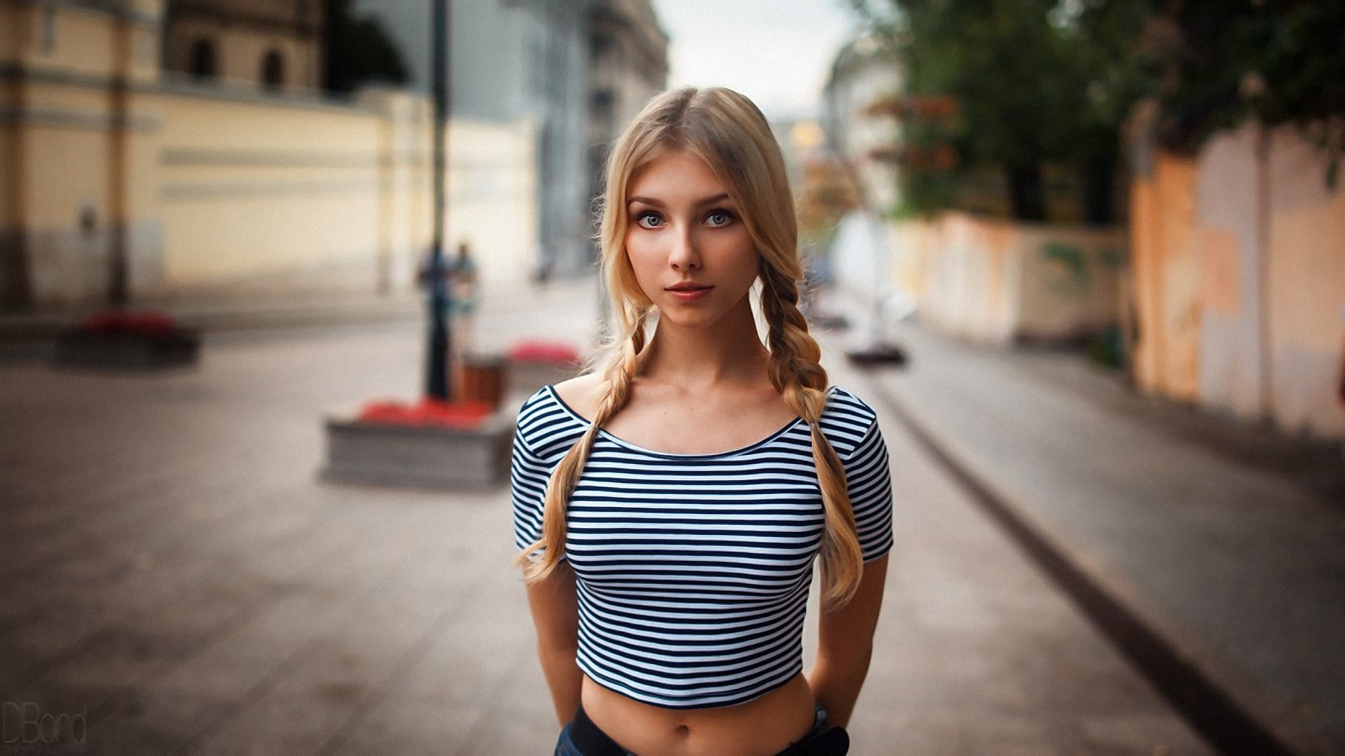 women's white and black striped top, selective focus photography of woman standing on street