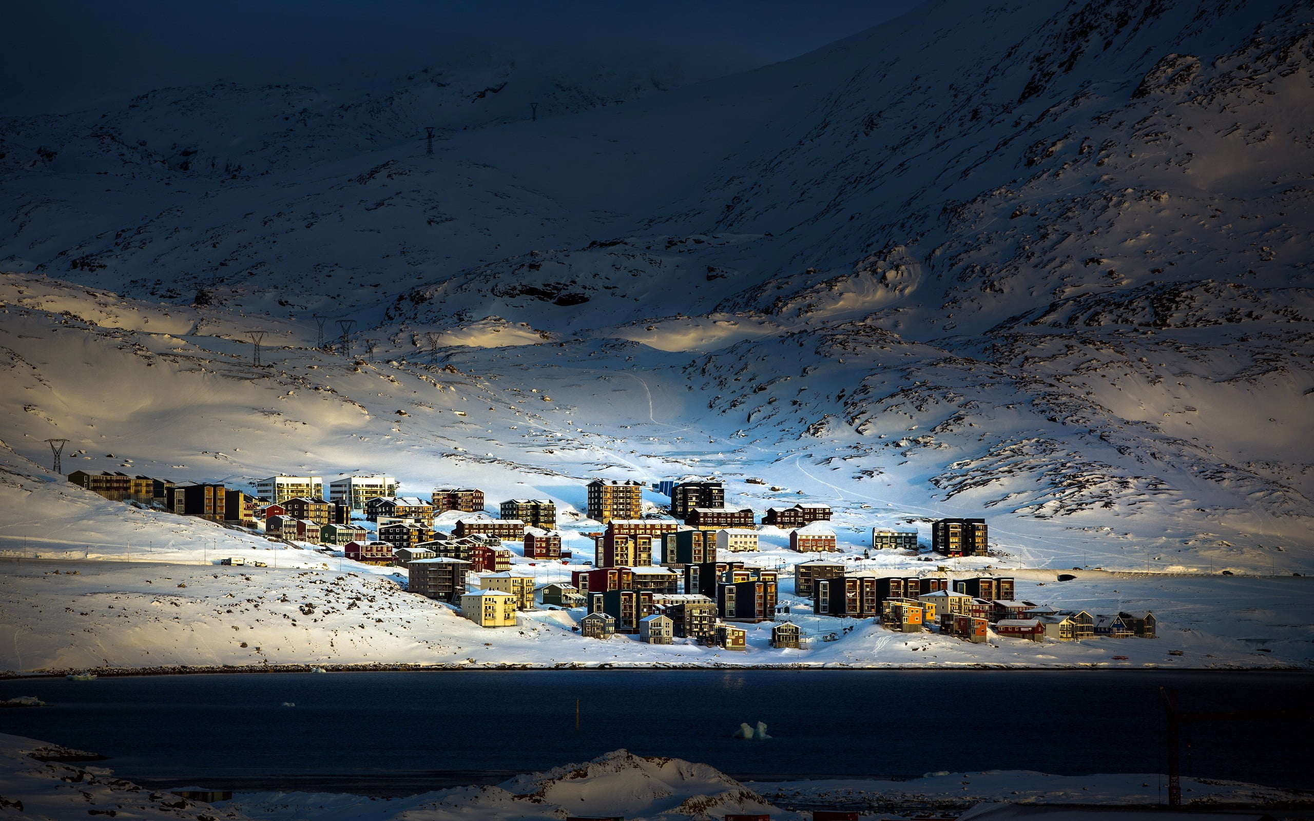 aerial photo of village on the foot of snowy mountain, Greenland