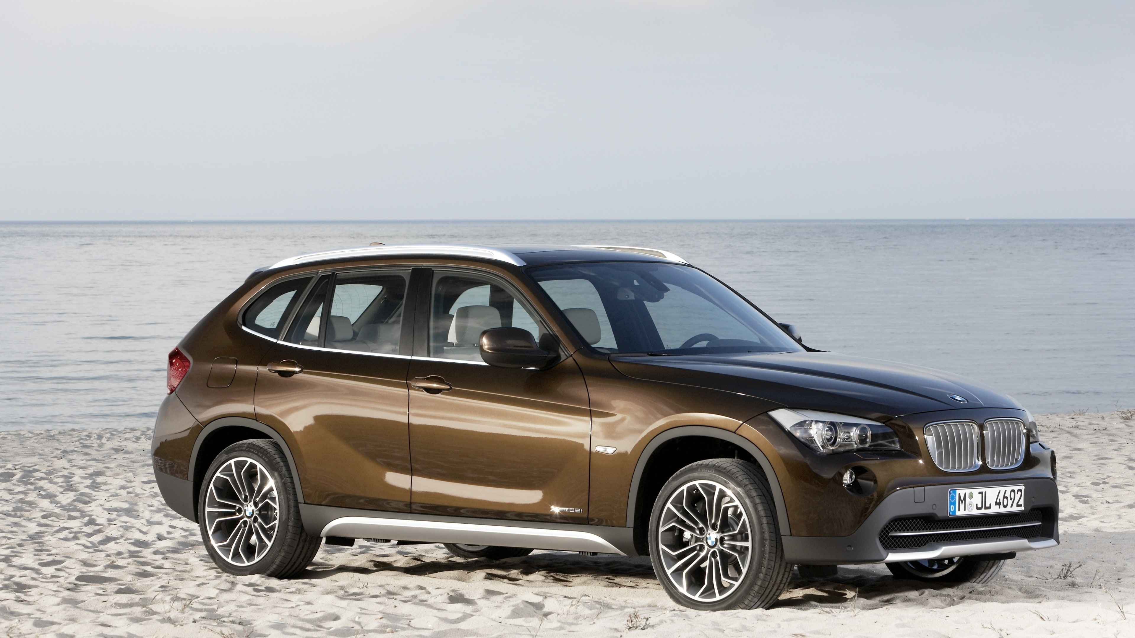 brown BMW SUV on white beach sand, BMW X1, crossover, luxury cars