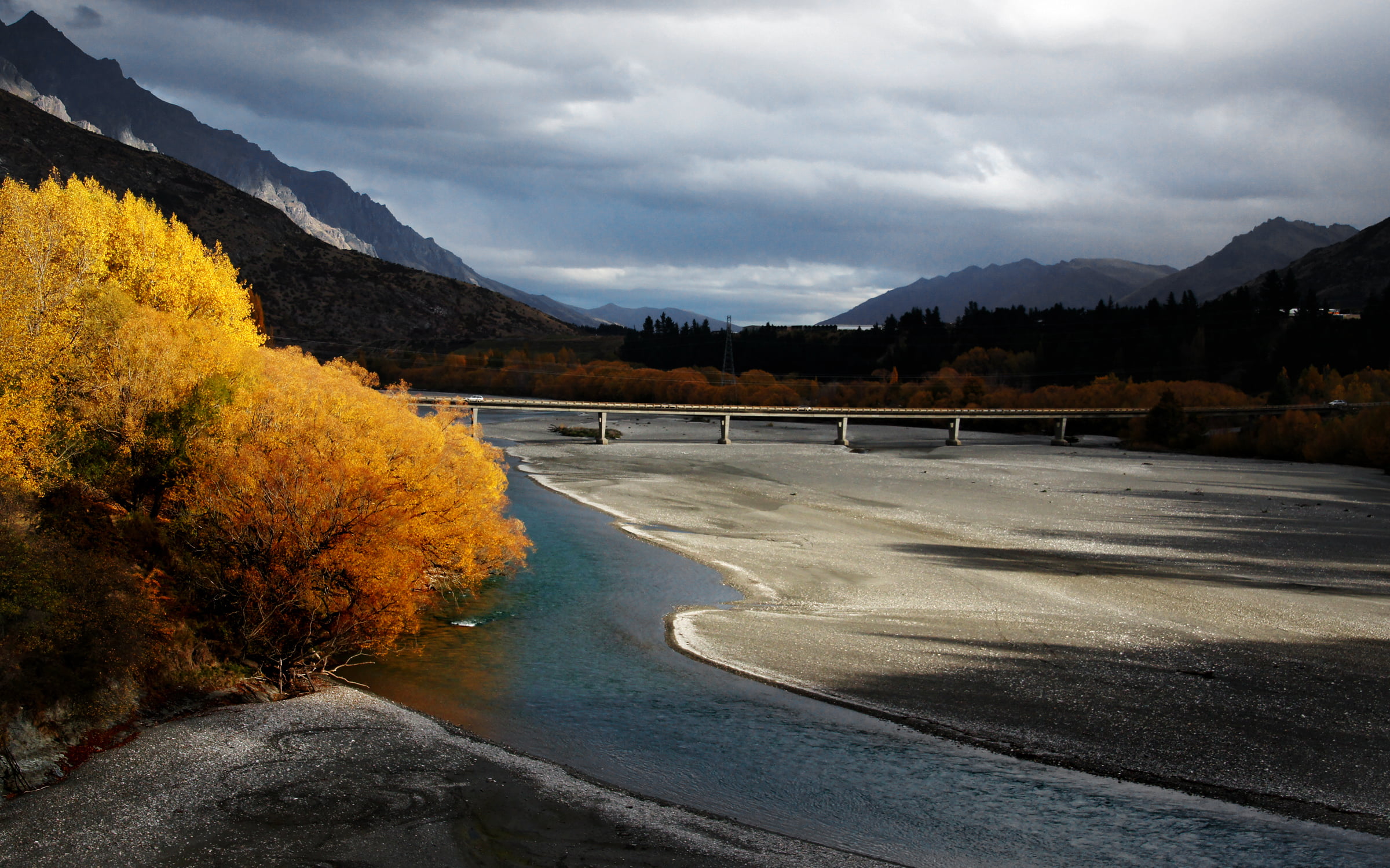 gray suspension bridge surrounded by mountains under white cloudy sky during daytime, shotover river, shotover river
