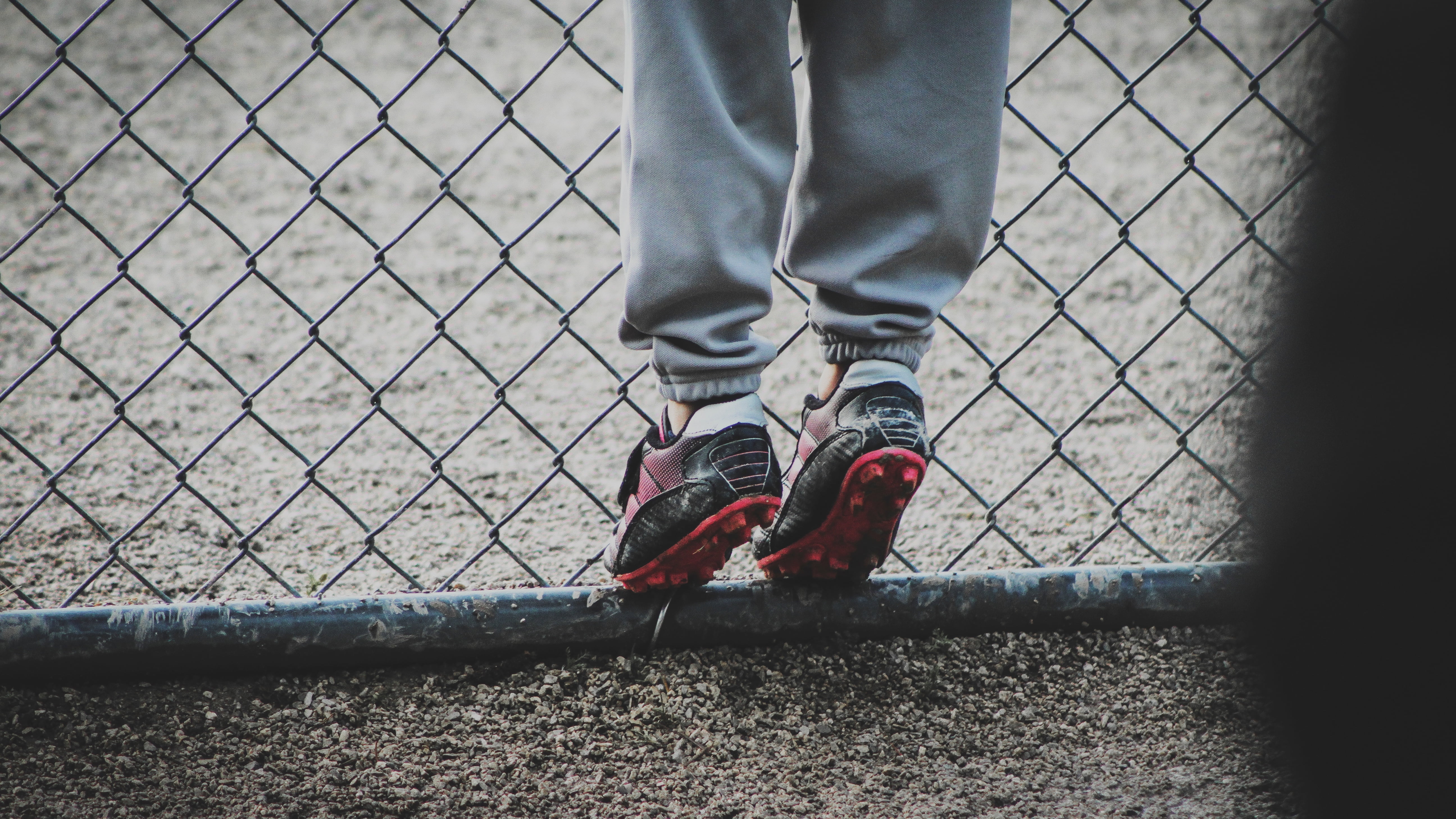 pair of black-and-red cleats, boots, feet, child, football, fence