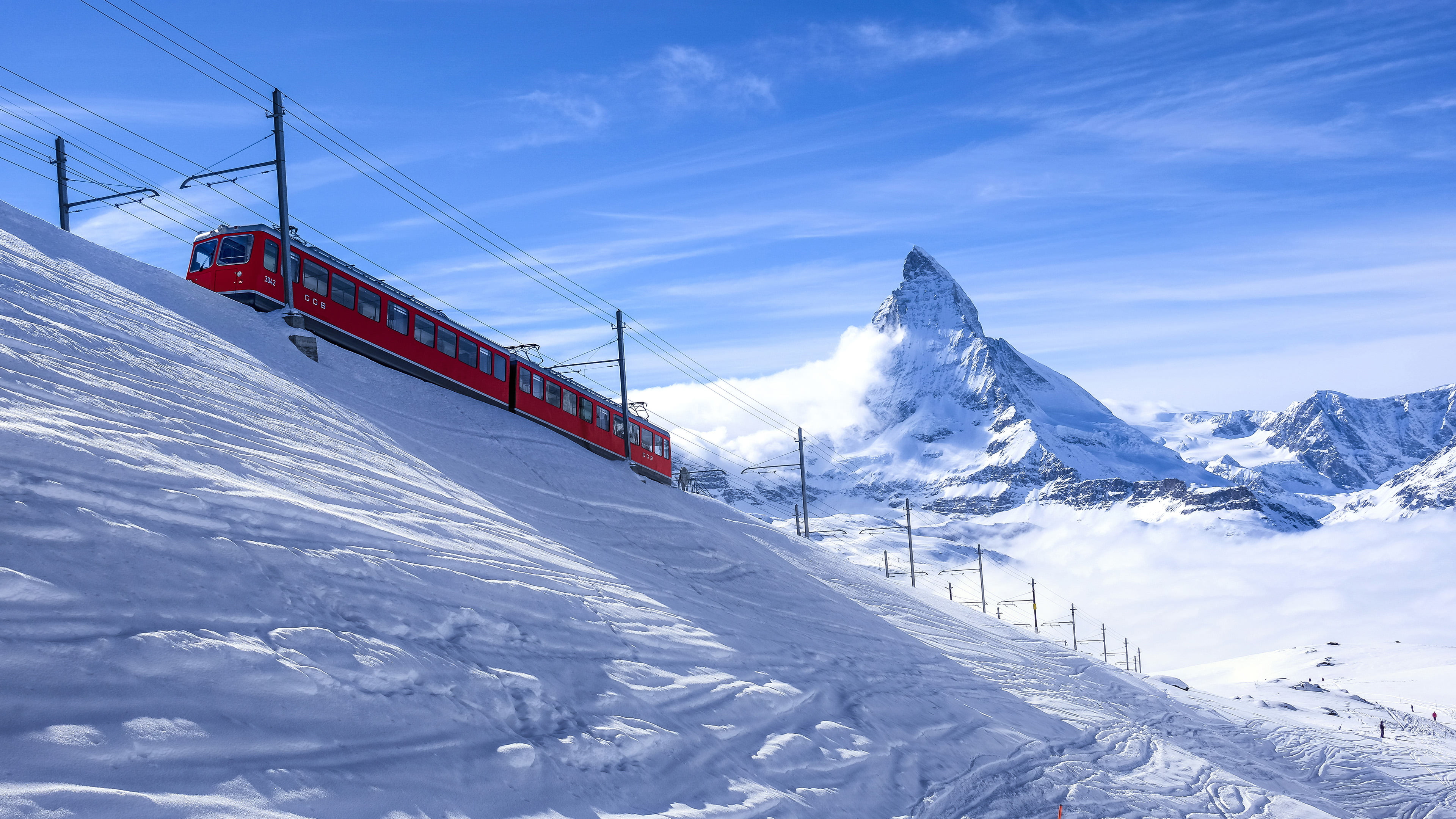 red and black train, red train and white mountains at daytime