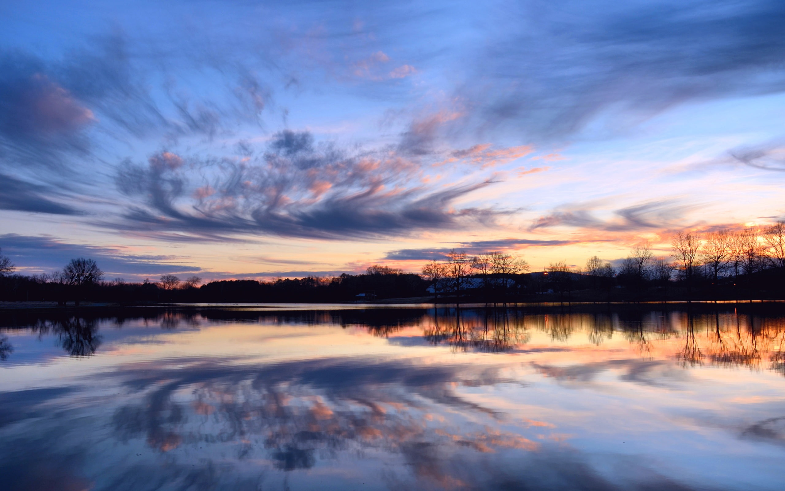Beautiful sunset, calm lake, reflection in the water, shore trees, sky clouds
