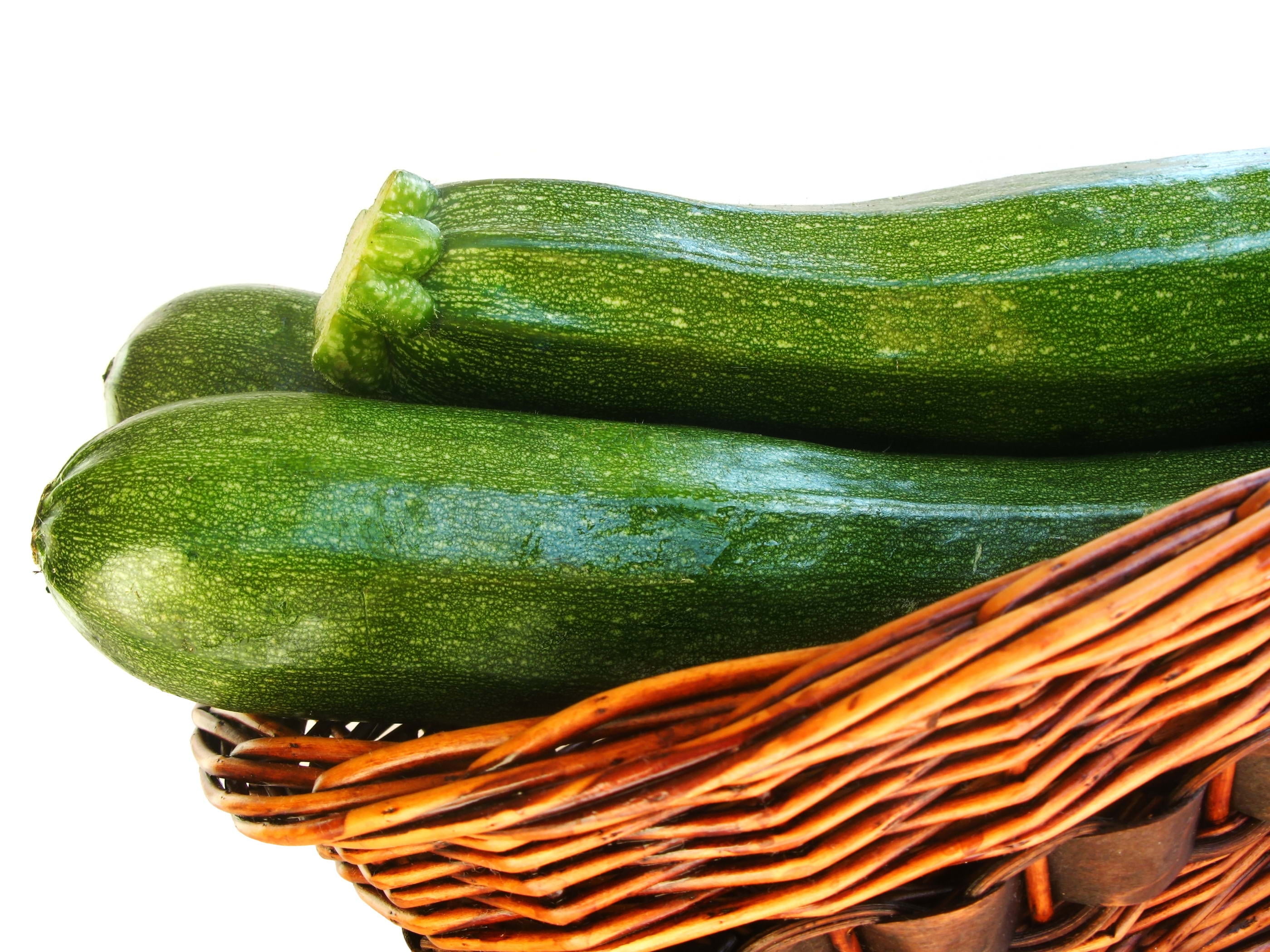three green cucumbers, squash, basket, white background, vegetable