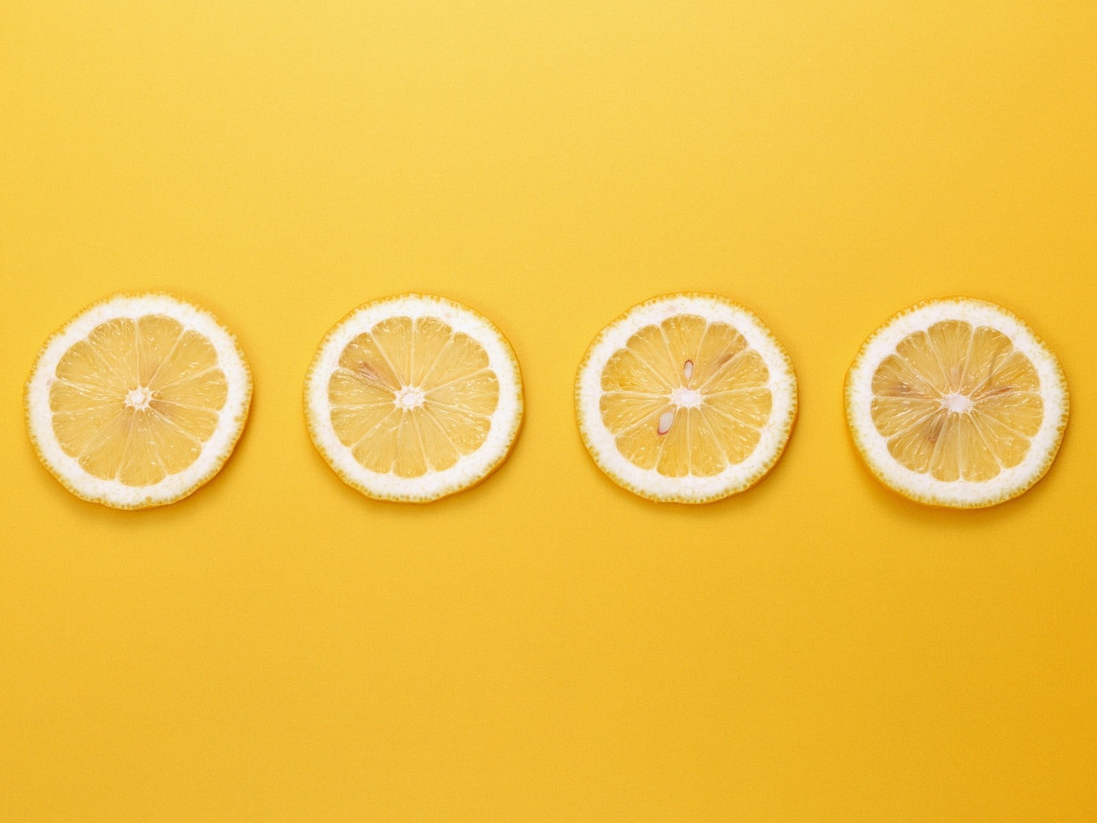 four slices of citrus fruit, yellow background, lemons, minimalism