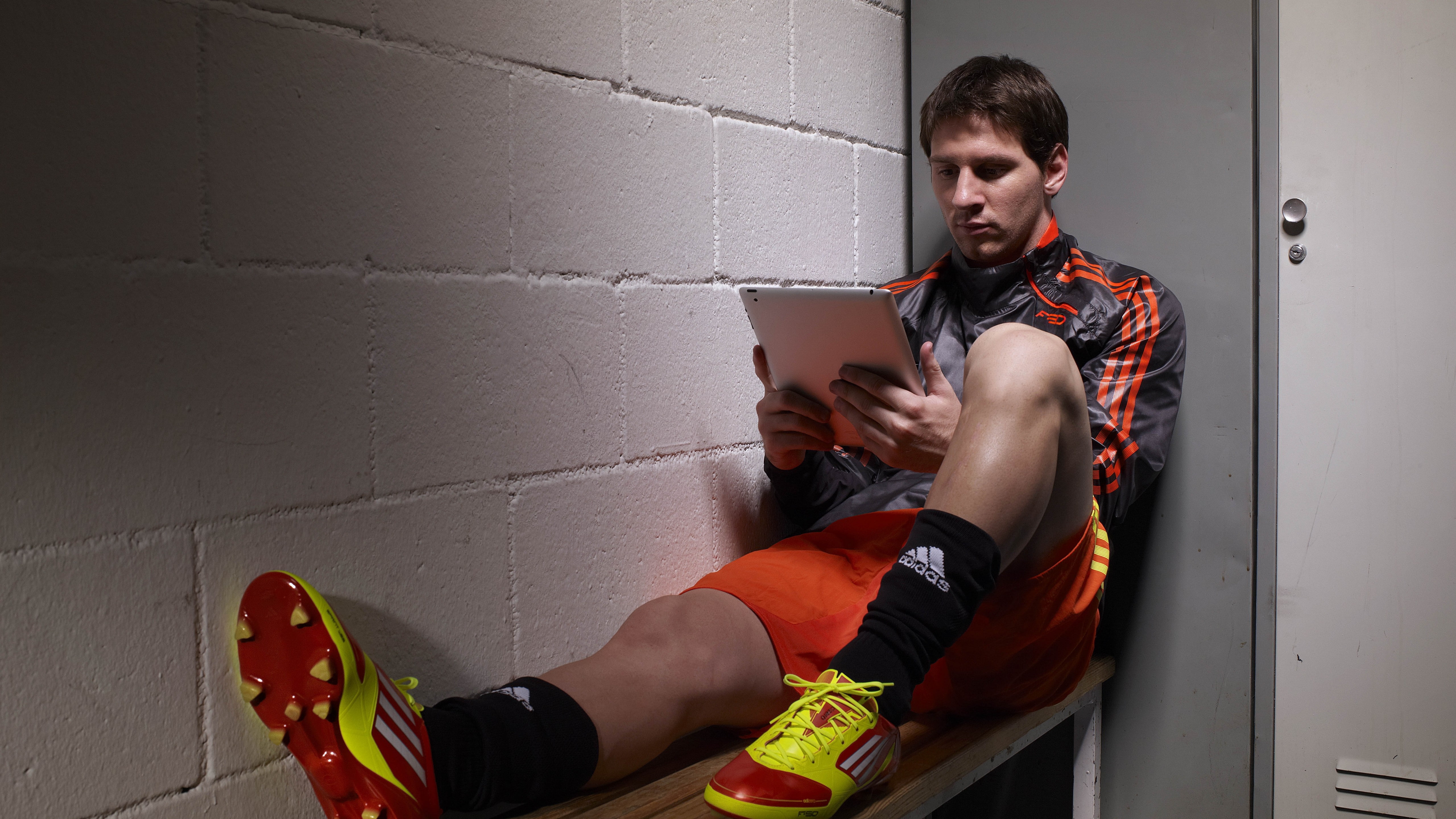 man wearing red-and-green soccer cleats while reading, Football